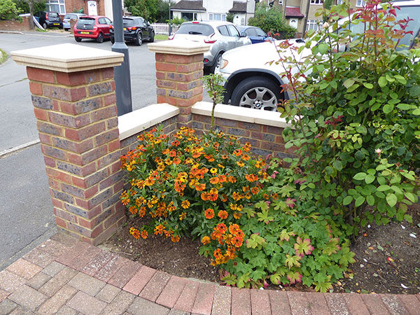 corner flower bed on front driveway with brick wall behind